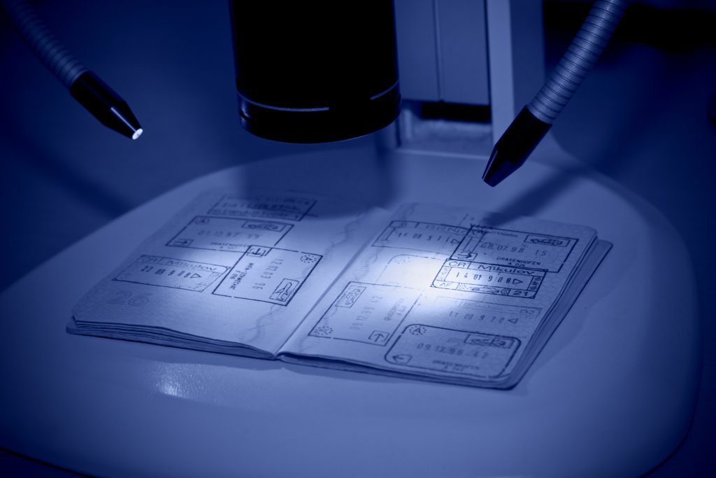 Toned image of passport being examined with a microscope.